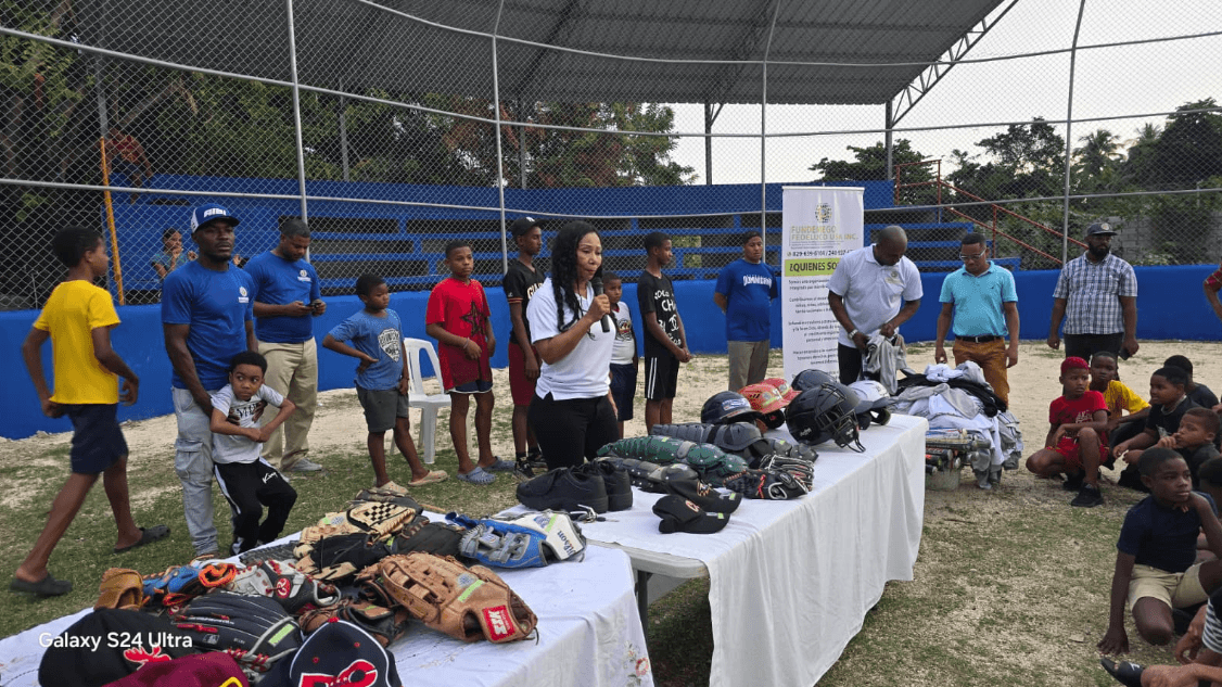Xiomara entrega equipamiento deportivo a niños en un campo de béisbol