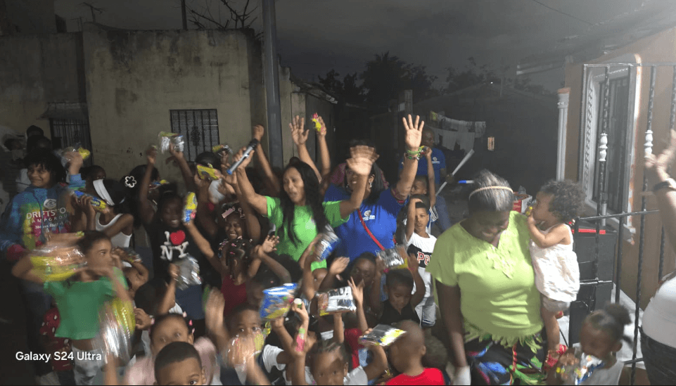 Niños y familias celebrando una entrega de regalos por la noche